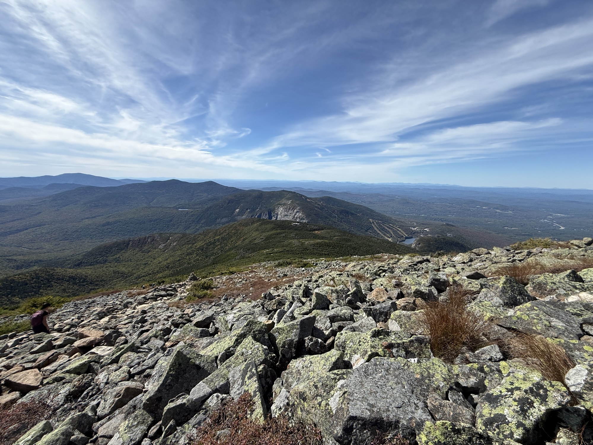 Rocky mountain slopes beneath a blue sky with wispy clouds.